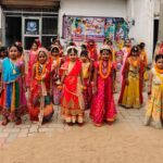 Group of children in bright traditional indian outfits posing in a row for a school cultural event on a courtyard